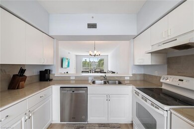 Kitchen with electric stove, dishwasher, white cabinets, a chandelier, and under cabinet range hood