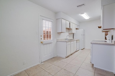 Kitchen featuring white cabinetry, light countertops, and light tile patterned floors