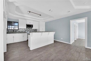 Main House Kitchen featuring white cabinets, a kitchen bar, a raised ceiling, and sink