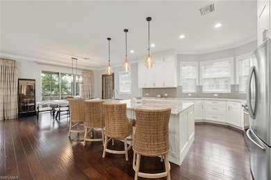 Kitchen featuring stainless steel appliances, dark wood finished floors, backsplash, light quartz counters, modern light fixtures and crown molding