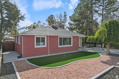 View of side of home featuring a shingled roof, stucco siding, a chimney, and a patio area