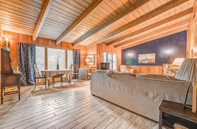 Living room with wooden walls, wood-type flooring, healthy amount of natural light, and wooden ceiling