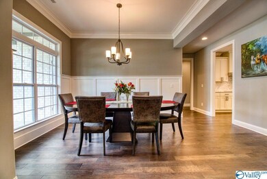 Dining room shows out with glowing hardwoods, dramatic natural light, and craftsman wainscot.