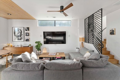 Living room with ceiling fan, stairs, and wood fi