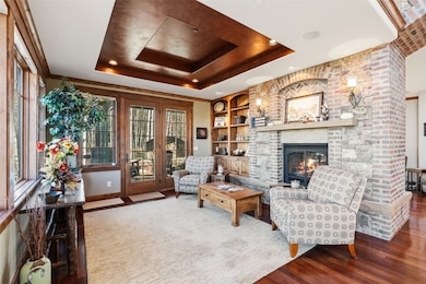 Living area with a tray ceiling, a fireplace, wood finished floors, and built in shelves