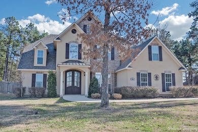 View of front of house featuring stucco siding, a shingled roof, and stone siding