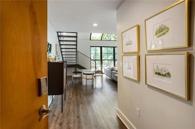Corridor featuring recessed lighting, wood finished floors, baseboards, and stairway