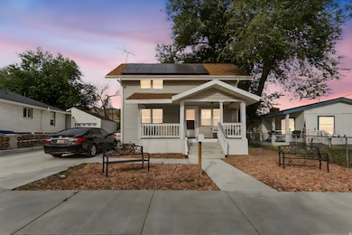View of front of property with covered porch, roof mounted solar panels, and concrete driveway