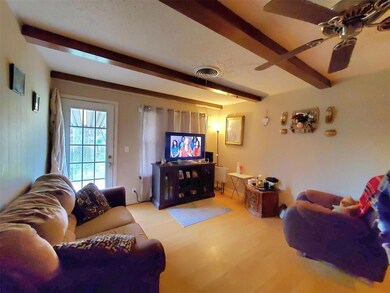 Living room with wood finished floors, beam ceilin