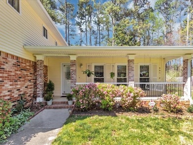 Doorway to property with covered porch and brick siding