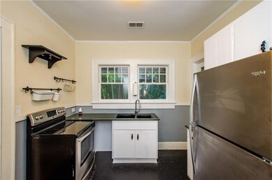 Kitchen with stainless steel appliances, white cabinets, dark countertops, and ornamental molding