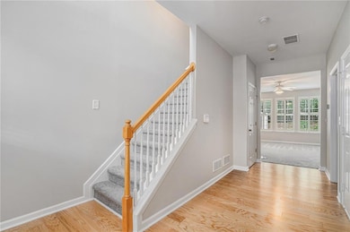 Stairs with wood finished floors and a ceiling fan