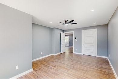 Empty room featuring ceiling fan and light wood-ty