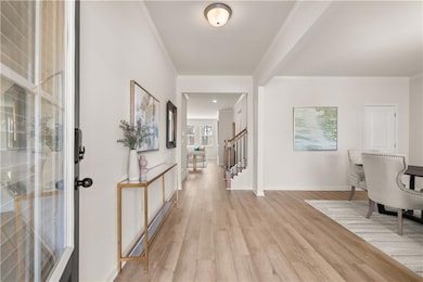 Entrance foyer with baseboards, light wood-style flooring, ornamental molding, and stairway