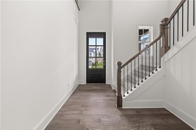 Entrance foyer with dark wood-type flooring, stairway, and a towering ceiling