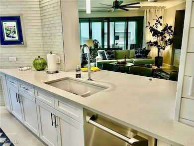 Kitchen with dishwasher, light stone countertops, white cabinetry, light tile patterned floors, and a ceiling fan