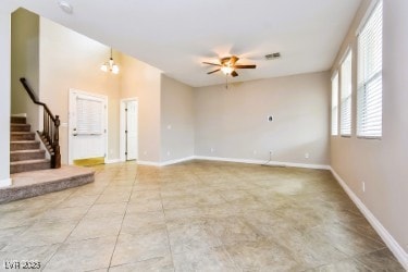Tiled empty room featuring ceiling fan and stairwa