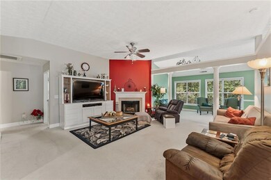 Living room with ceiling fan, carpet, decorative columns, and a fireplace