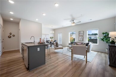 Kitchen with an island with sink, gray cabinets, light stone countertops, a kitchen breakfast bar, and pendant lighting