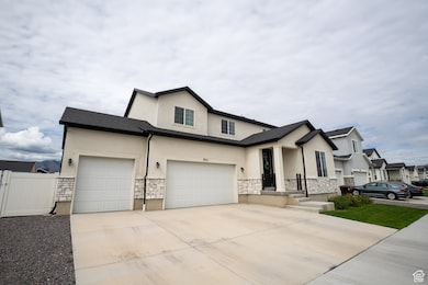 View of front of home featuring stone siding, concrete driveway, stucco siding, and a gate