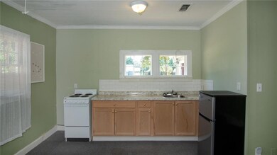 Kitchen with white electric stove, light countertops, crown molding, and freestanding refrigerator