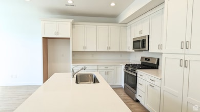 Kitchen featuring stainless steel appliances, light wood-style flooring, recessed lighting, and white cabinets (pictures are of a previous home built)