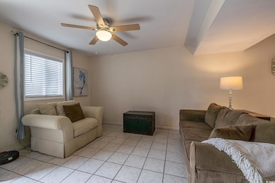 Living room with ceiling fan and light tile patter