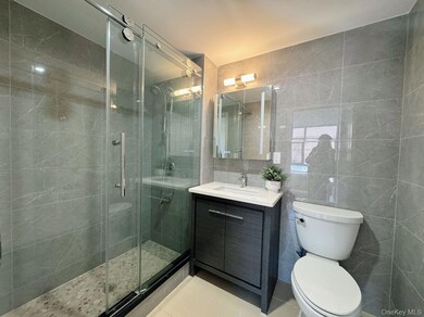 Bathroom featuring tile walls, a shower stall, toilet, tile patterned floors, and vanity
