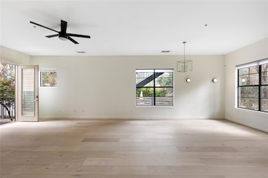 Empty room featuring light wood-style floors, plenty of natural light, and a ceiling fan