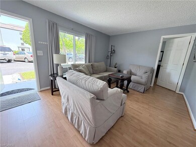 Living area featuring light wood finished floors, a textured ceiling, and baseboards
