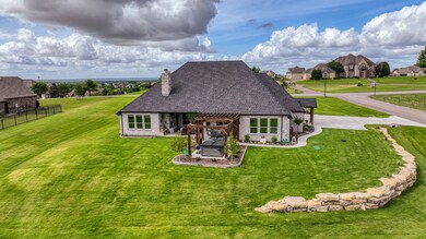 Back elevation showing sodded and irrigated lot with large stone retaining wall on garage side.