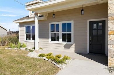 View of exterior entry featuring a yard, roof with shingles, and stone siding