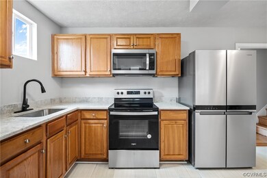 Kitchen with sink, a textured ceiling, light stone countertops, light tile floors, and stainless steel appliances