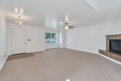 Unfurnished living room with a fireplace, carpet flooring, a chandelier, and ceiling fan
