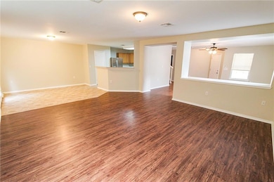 Unfurnished living room with dark wood-style flooring and ceiling fan