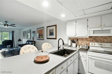 Kitchen featuring white appliances, open floor plan, white cabinetry, a peninsula, and light countertops