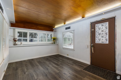Entryway featuring dark wood-type flooring and wood walls