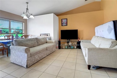 Living area with light tile patterned floors, lofted ceiling, and a chandelier