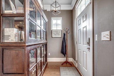 Entryway featuring baseboards, ornamental molding, a chandelier, and wood finished floors