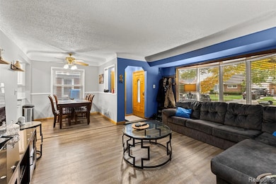 Living room with wood finished floors, ceiling fan, and a textured ceiling