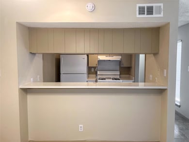 Kitchen featuring white appliances, under cabinet range hood, light stone counters, a peninsula, and cream cabinetry