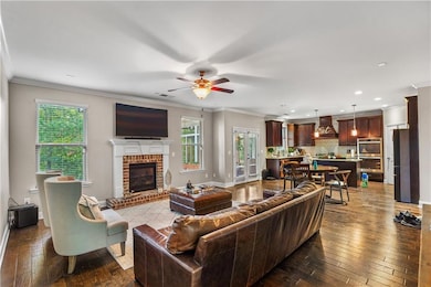 Living room featuring dark wood finished floors, ornamental molding, a ceiling fan, a brick fireplace, and recessed lighting