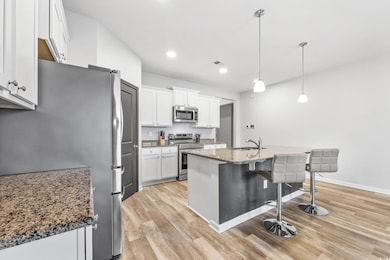 Kitchen featuring white cabinets, hanging light fi