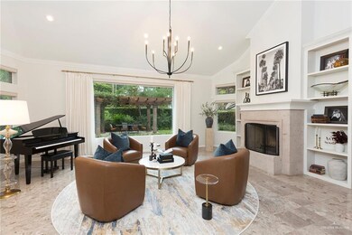 Conversation room featuring a woodburning fireplace, bookshelves, chandelier, electric blinds & picture window featuring the lush backyard