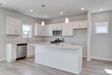 Kitchen with white cabinetry, appliances with stai