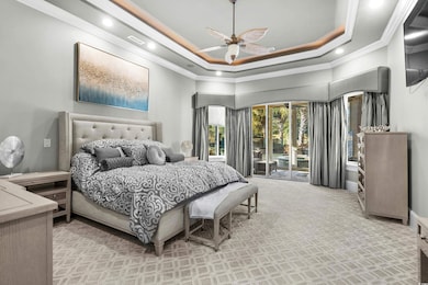 Bedroom with crown molding, access to outside, a towering ceiling, a ceiling fan, and a raised ceiling