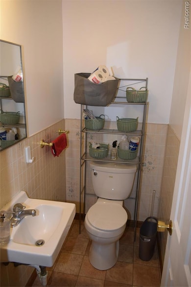 Bathroom featuring wainscoting, tile walls, and light tile patterned floors