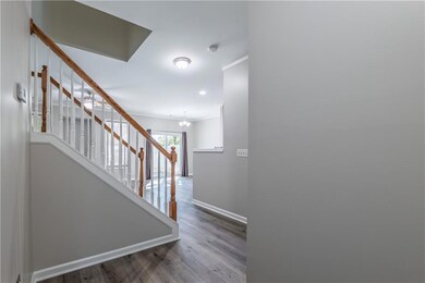 Stairway with a chandelier, wood finished floors, and ornamental molding