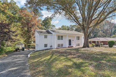 Split foyer home featuring a front yard, asphalt driveway, and an outdoor structure