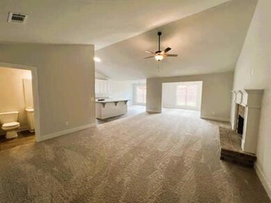 Unfurnished living room with dark carpet, vaulted ceiling, a fireplace, and ceiling fan